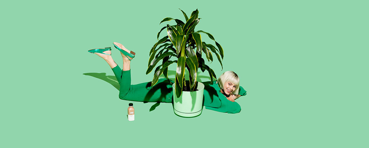 Woman hiding behind a potted plant.