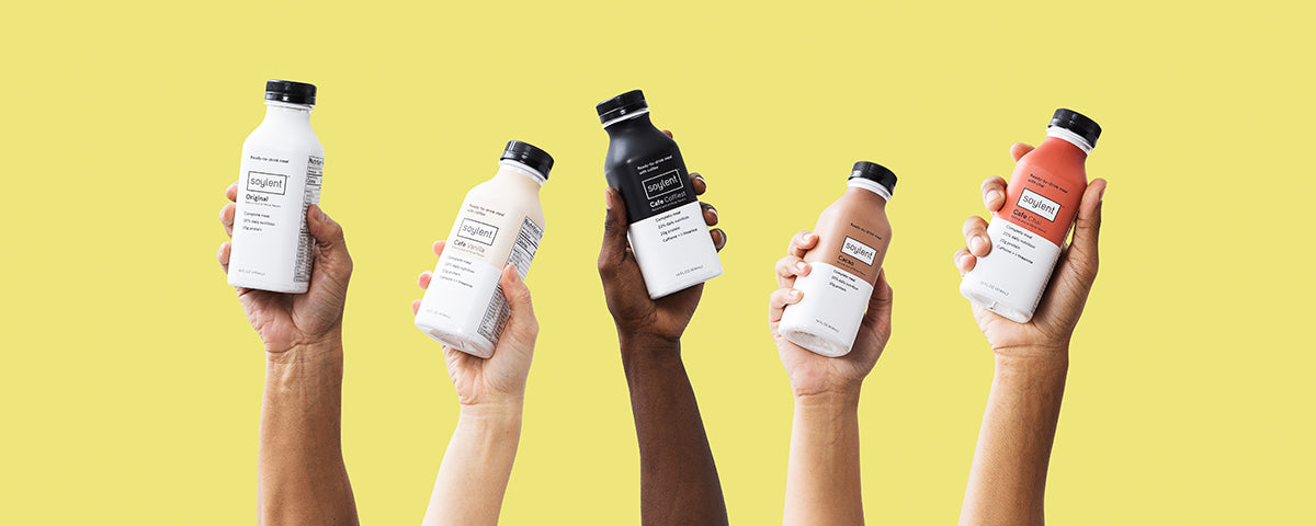 Hands holding up bottles of Soylent