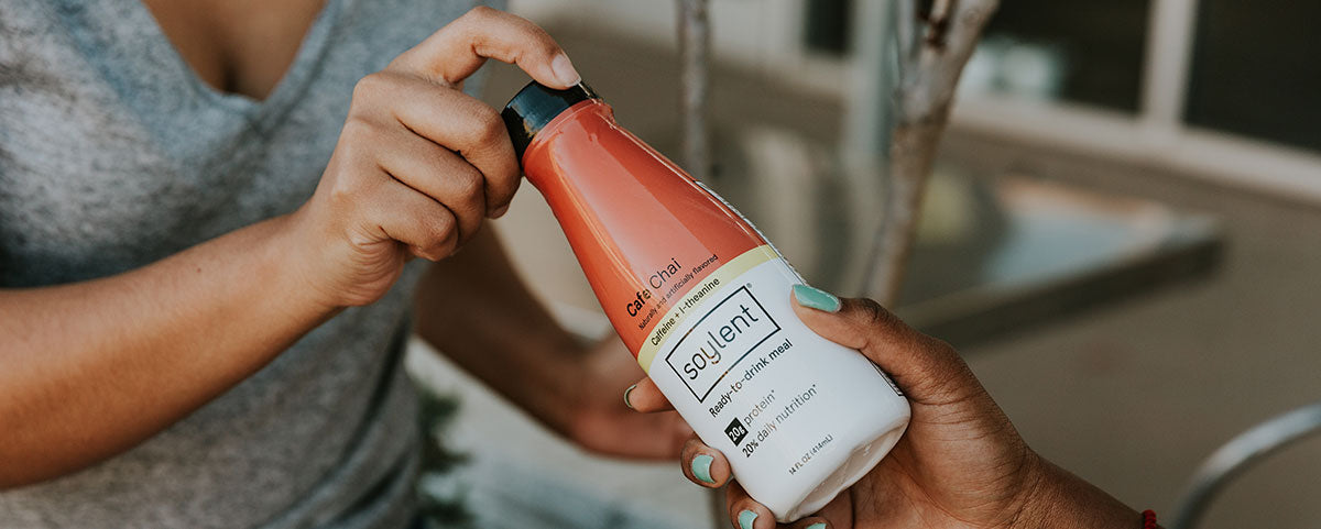 A woman handing a bottle of Soylent to a person in need