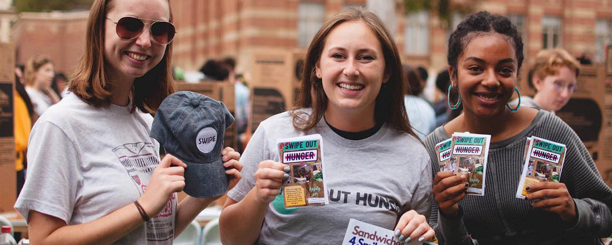 Happy students holding up gifts from Swipe Out Hunger and Soylent